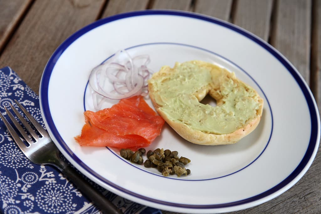 Open bagel with smoked salmon, avocado cream cheese, capers and red onion